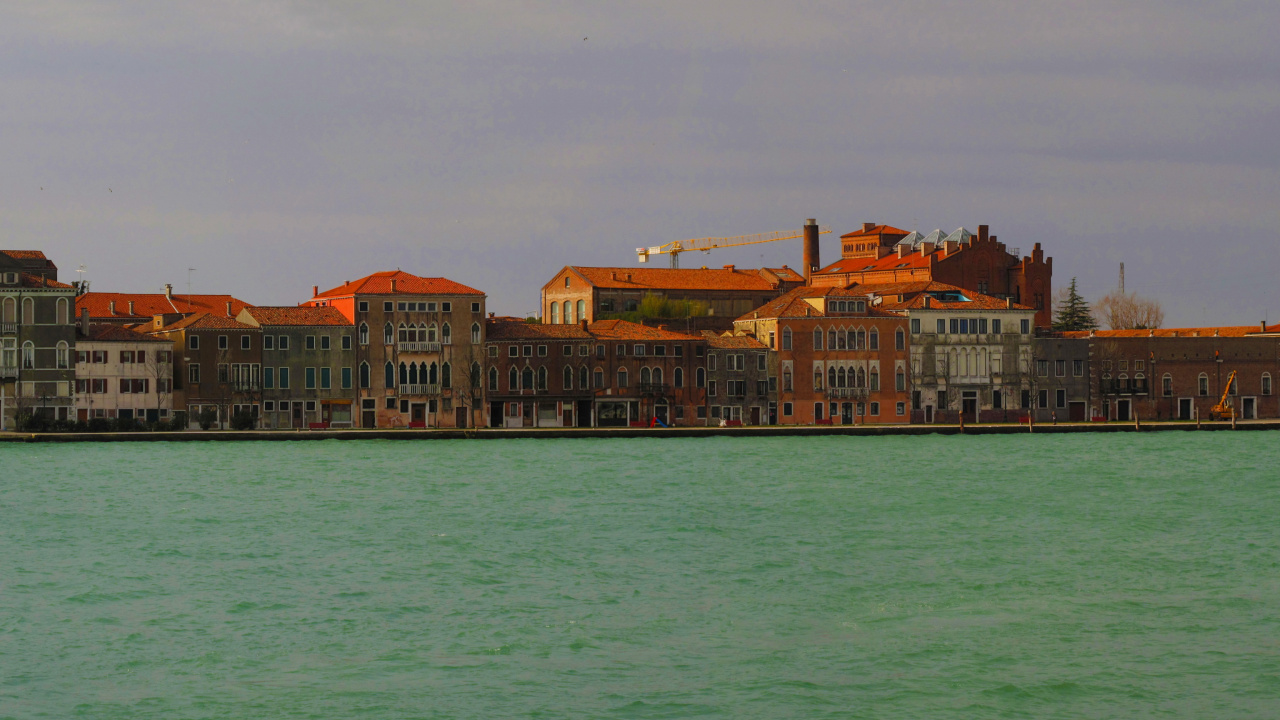 Brown and White Concrete Building Beside Body of Water During Daytime. Wallpaper in 1280x720 Resolution