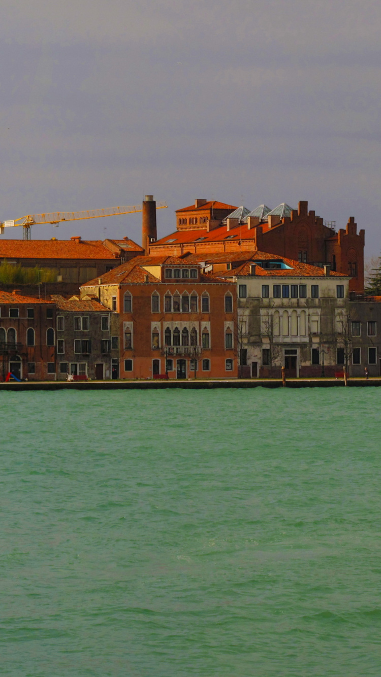 Brown and White Concrete Building Beside Body of Water During Daytime. Wallpaper in 750x1334 Resolution