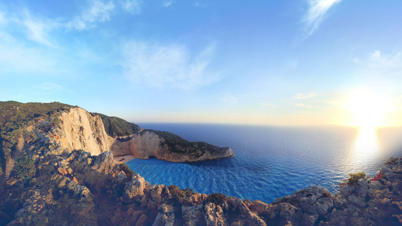 Brown Rocky Mountain Beside Blue Sea Under Blue Sky During Daytime. Wallpaper in 1366x768 Resolution