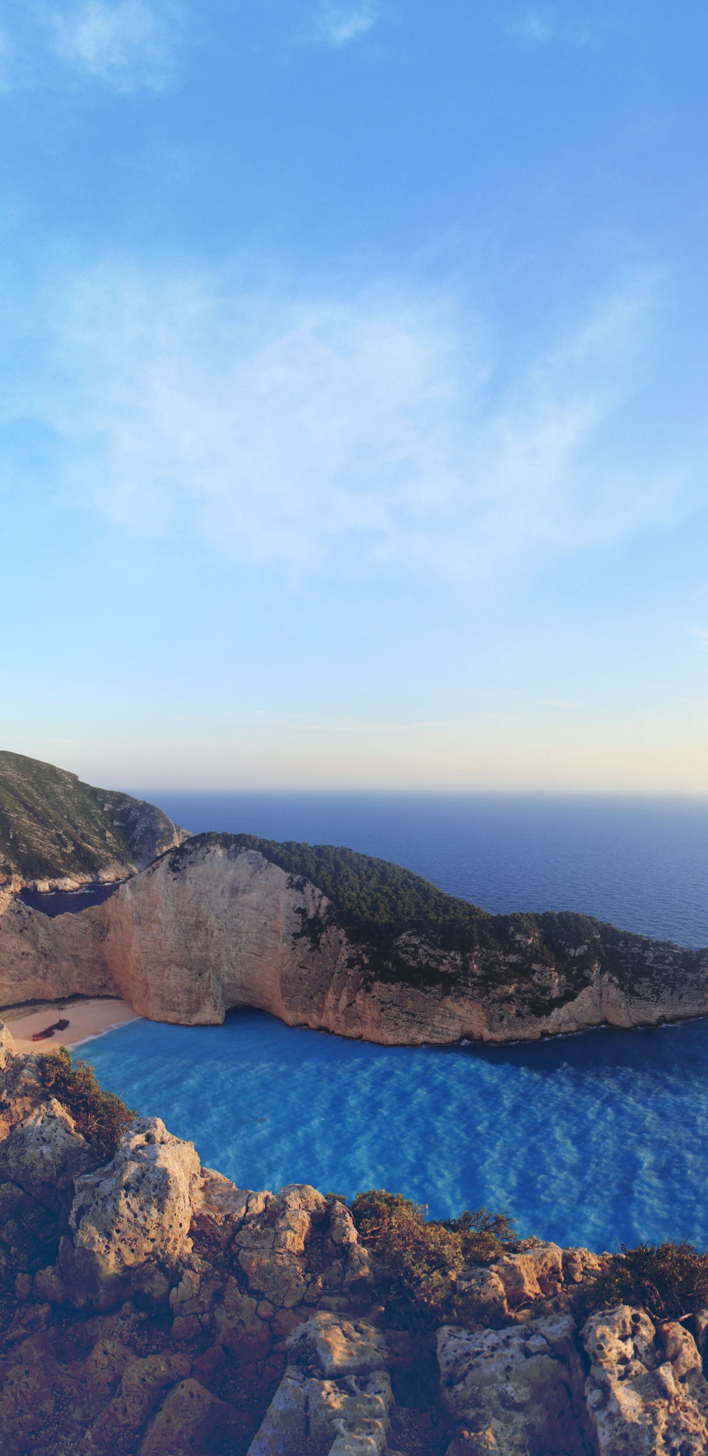 Brown Rocky Mountain Beside Blue Sea Under Blue Sky During Daytime. Wallpaper in 1440x2960 Resolution