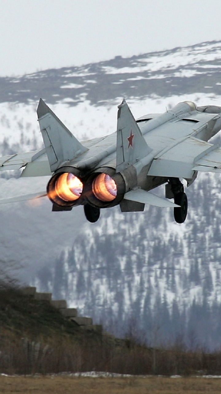 Graues Kampfflugzeug, Das Tagsüber Über Schneebedeckten Boden Fliegt. Wallpaper in 720x1280 Resolution