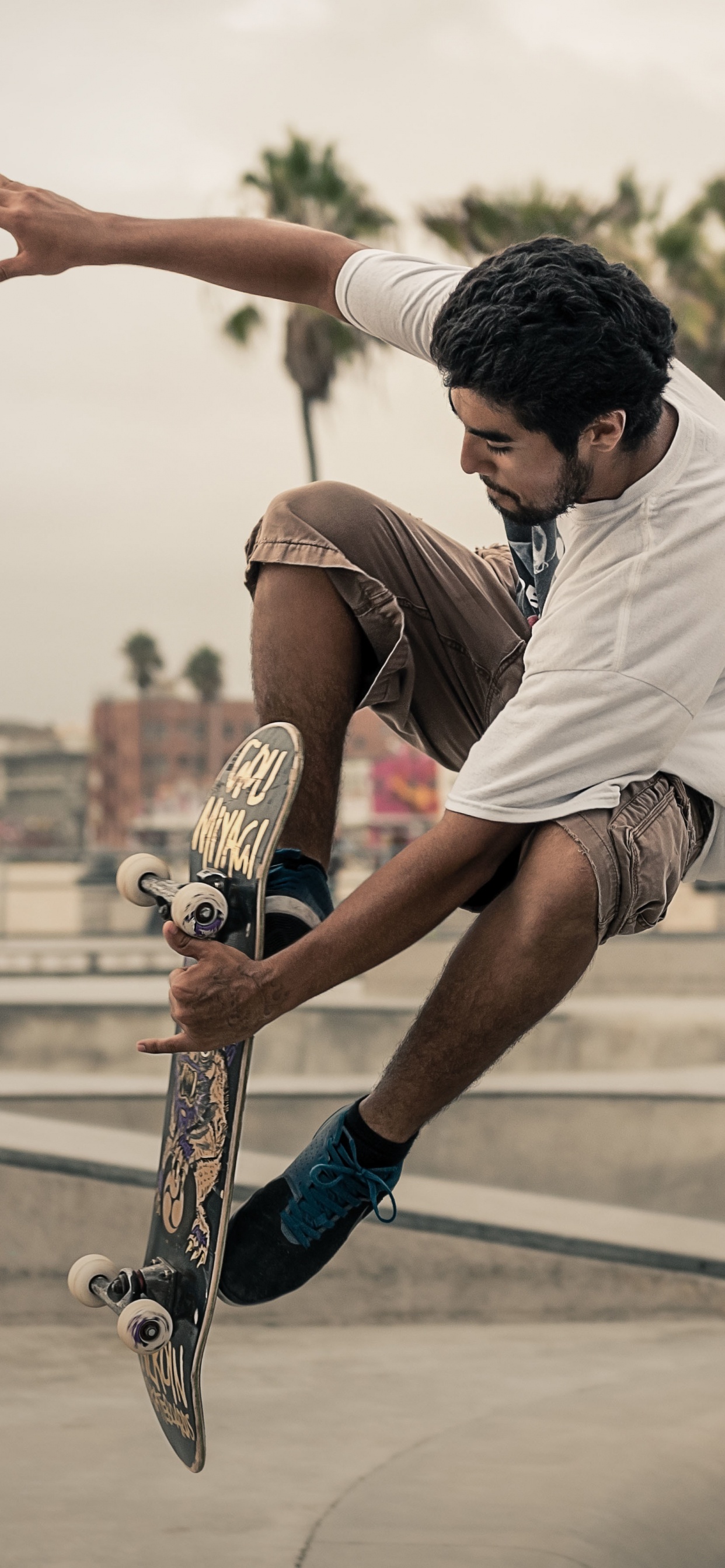 Mann in Weißem T-Shirt Und Braunen Shorts, Der Tagsüber Skateboard Spielt. Wallpaper in 1242x2688 Resolution
