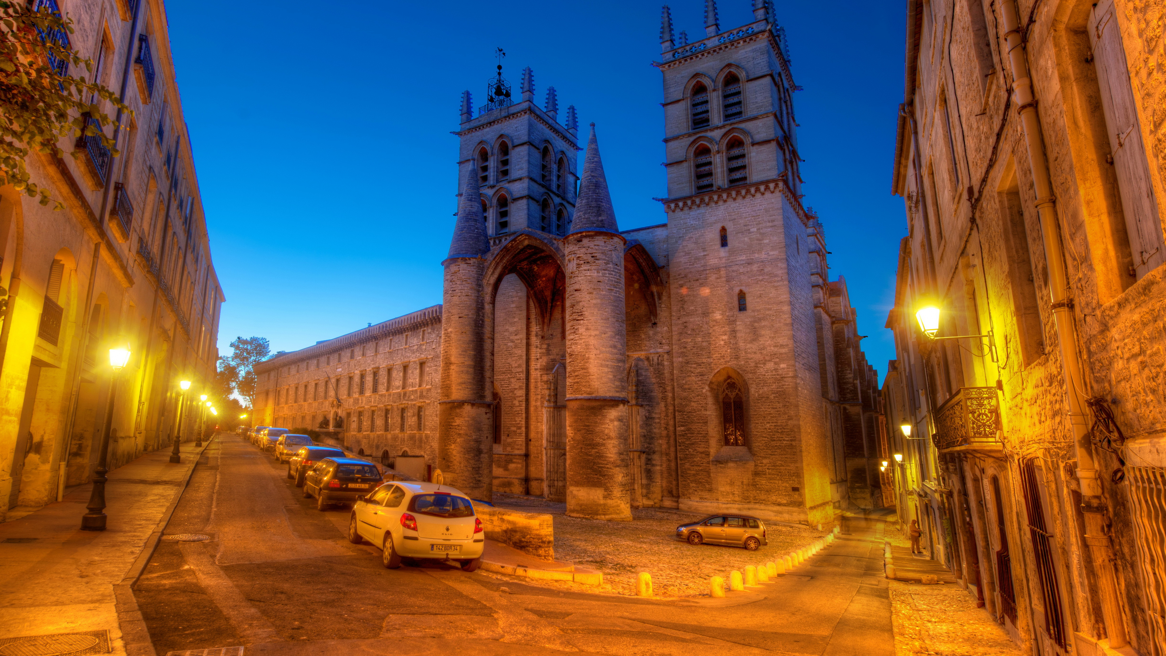 Coches Aparcados Junto a un Edificio de Hormigón Marrón Durante la Noche. Wallpaper in 3840x2160 Resolution