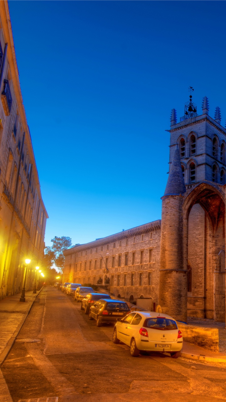 Coches Aparcados Junto a un Edificio de Hormigón Marrón Durante la Noche. Wallpaper in 720x1280 Resolution