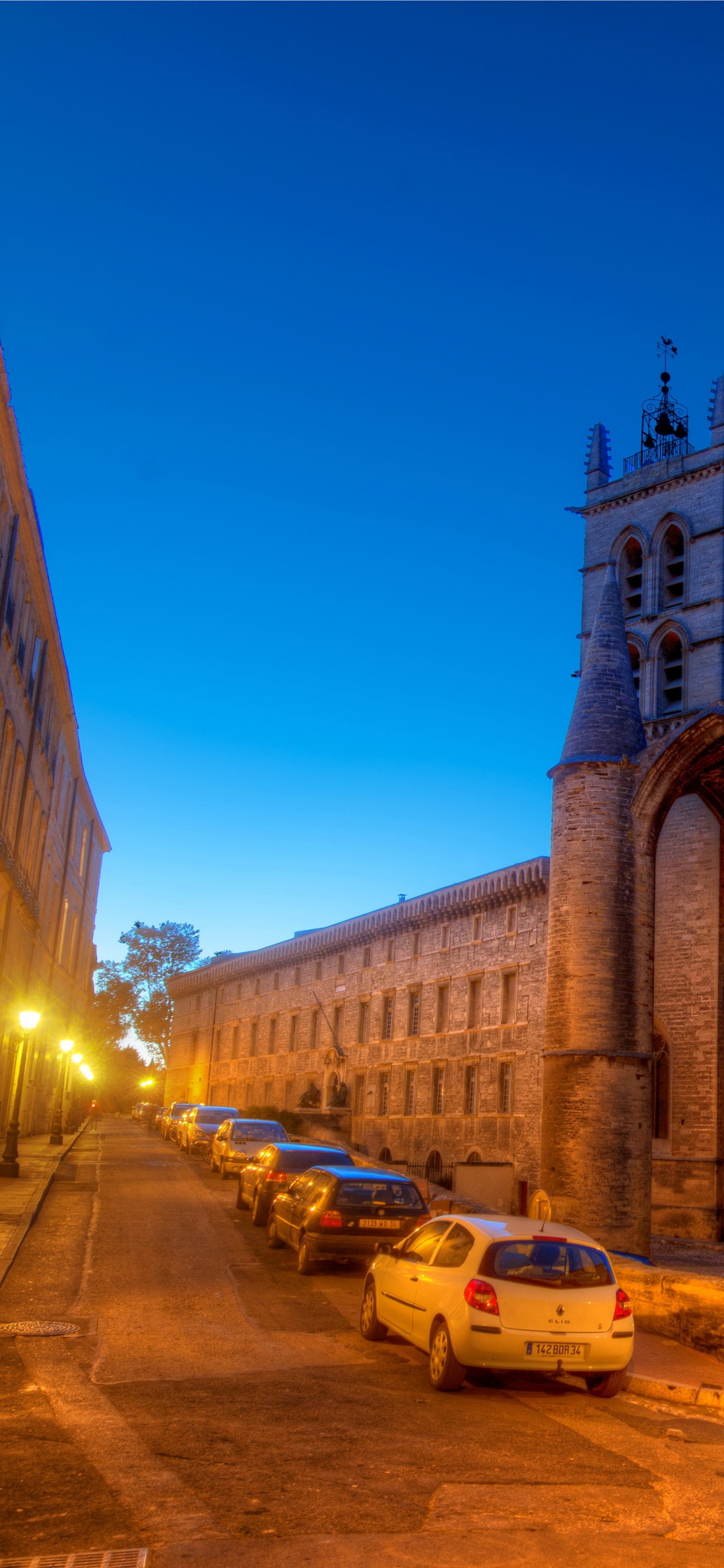 Voitures Garées à Côté D'un Bâtiment en Béton Brun Pendant la Nuit. Wallpaper in 1125x2436 Resolution