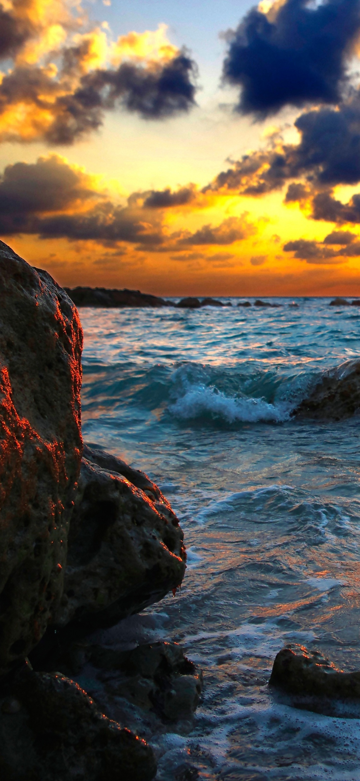 Rocky Shore Under Cloudy Sky During Sunset. Wallpaper in 1242x2688 Resolution