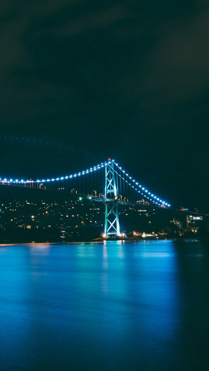 Lighted Bridge Over Water During Night Time. Wallpaper in 720x1280 Resolution