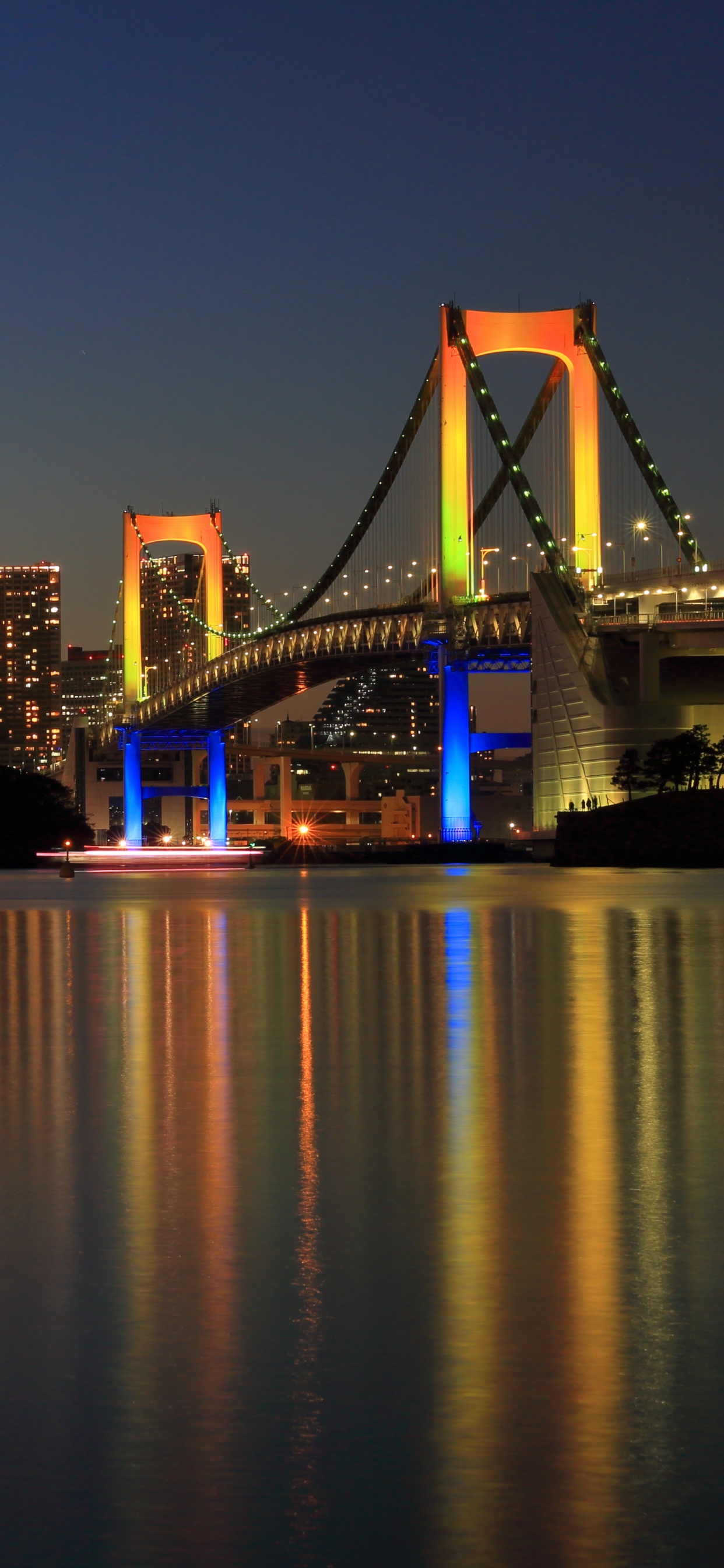 Pont Éclairé Au-dessus de L'eau Pendant la Nuit. Wallpaper in 1242x2688 Resolution