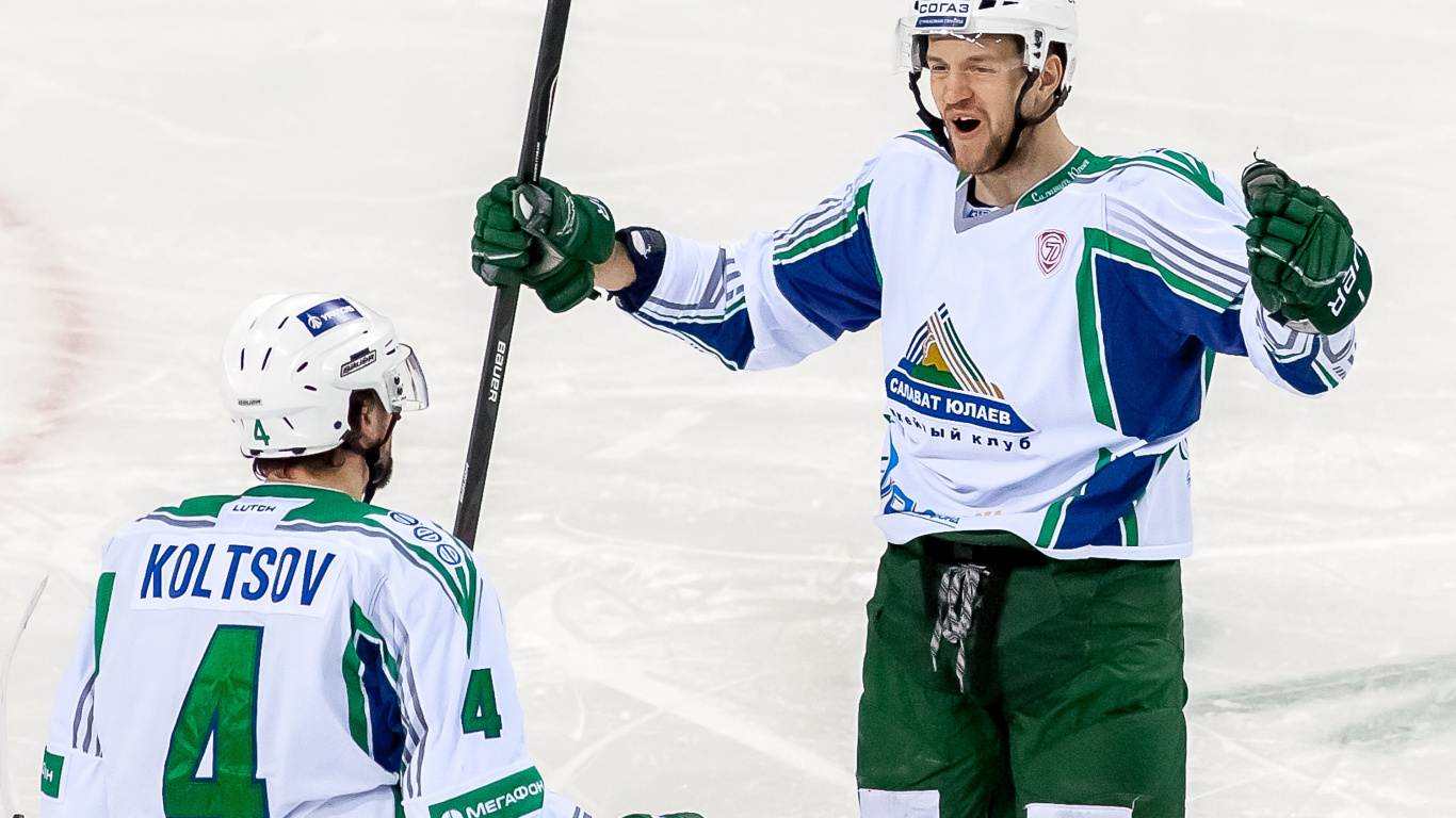 Man in White and Blue Jersey Shirt and Green Pants Holding Black and White Hockey Stick. Wallpaper in 1366x768 Resolution