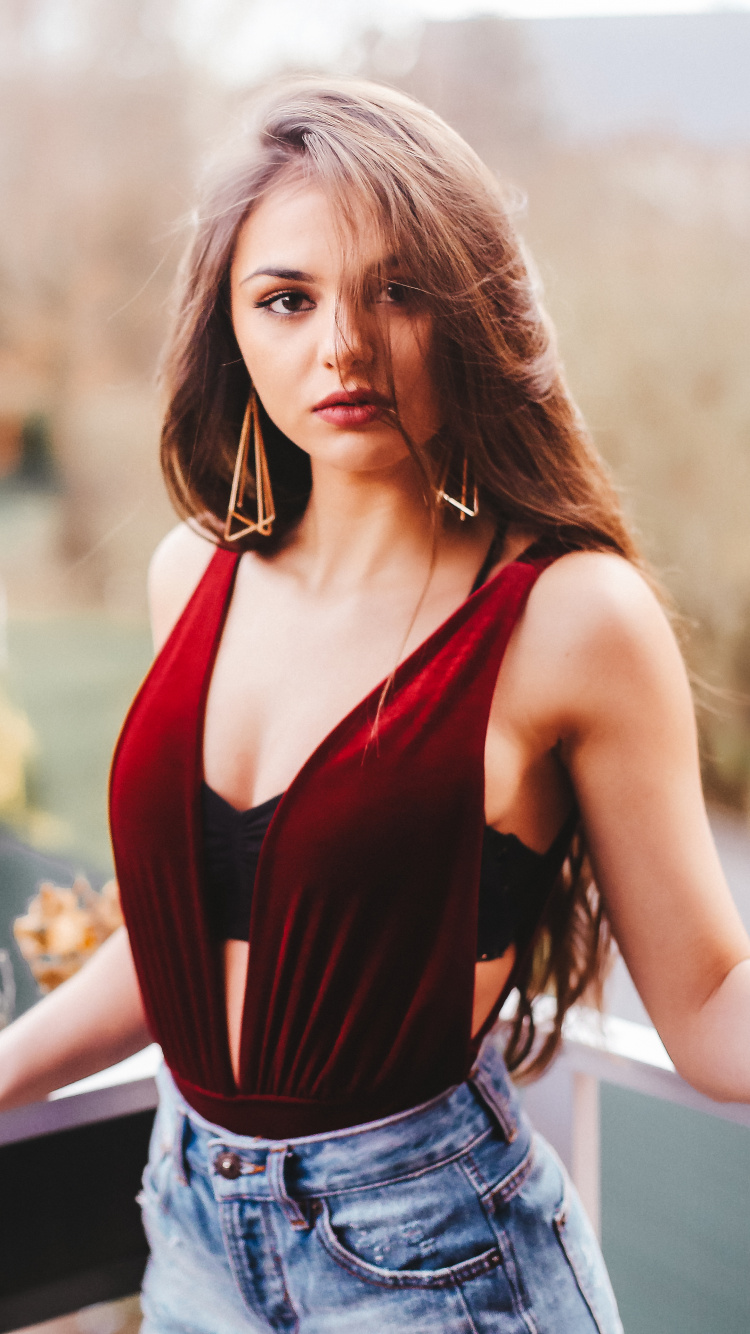 Mujer en Rojo Camiseta Sin Mangas y Pantalones Cortos de Mezclilla Azul de Pie Junto a Las Barandillas de Madera Blanca Durante el Día. Wallpaper in 750x1334 Resolution