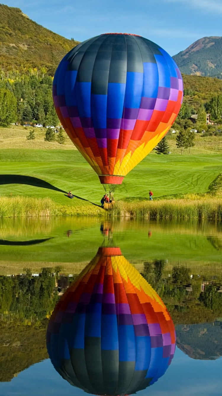 Globo de Aire Caliente Volando Sobre el Campo de Hierba Verde Durante el Día. Wallpaper in 750x1334 Resolution