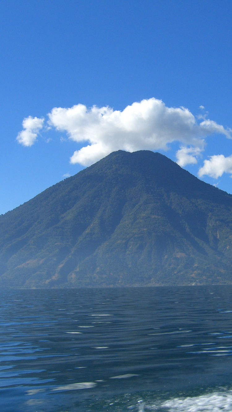 Montaña Cerca Del Cuerpo de Agua Bajo un Cielo Azul Durante el Día. Wallpaper in 750x1334 Resolution
