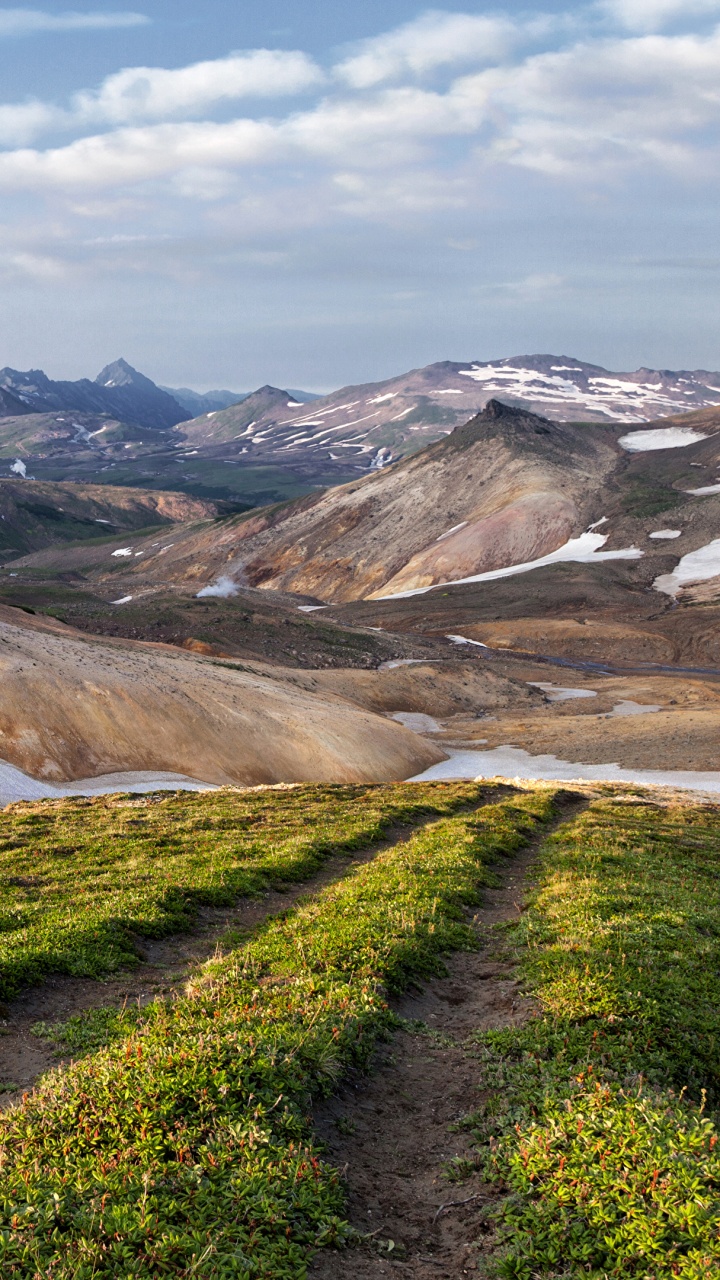 Campo de Hierba Verde Cerca de la Montaña Marrón Bajo Nubes Blancas Durante el Día. Wallpaper in 720x1280 Resolution