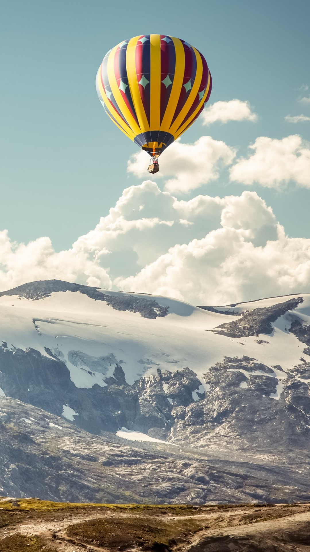 Yellow Blue and Red Hot Air Balloon Over Snow Covered Mountain. Wallpaper in 1080x1920 Resolution