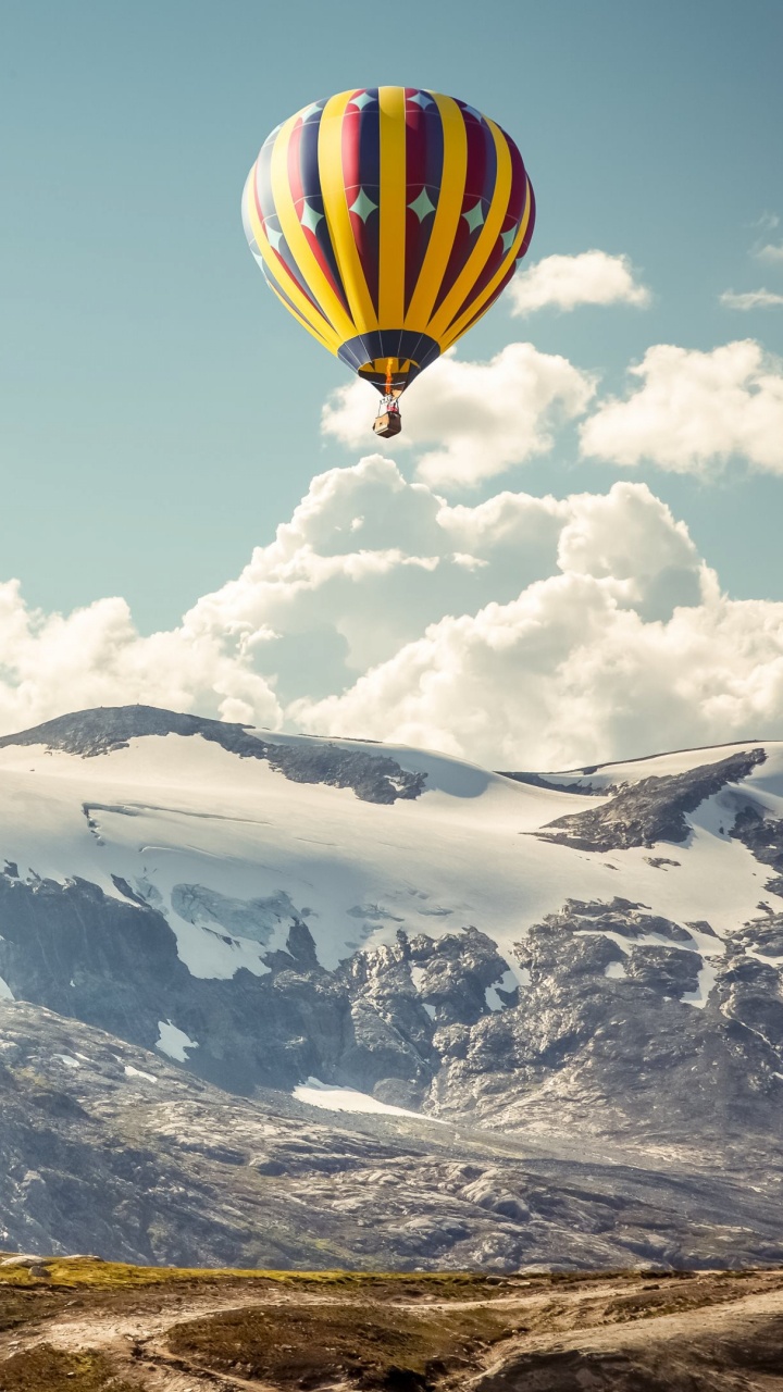 Yellow Blue and Red Hot Air Balloon Over Snow Covered Mountain. Wallpaper in 720x1280 Resolution