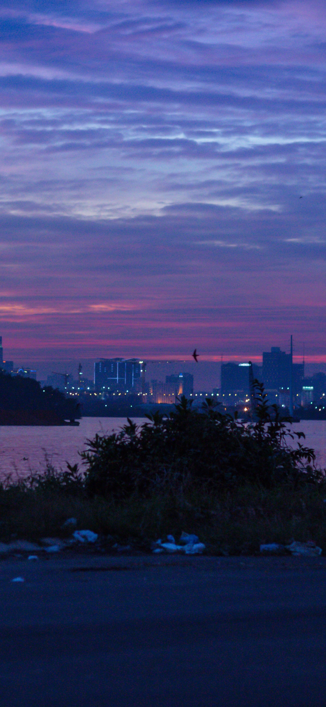 Skyline Der Stadt Unter Bewölktem Himmel Bei Sonnenuntergang. Wallpaper in 1125x2436 Resolution