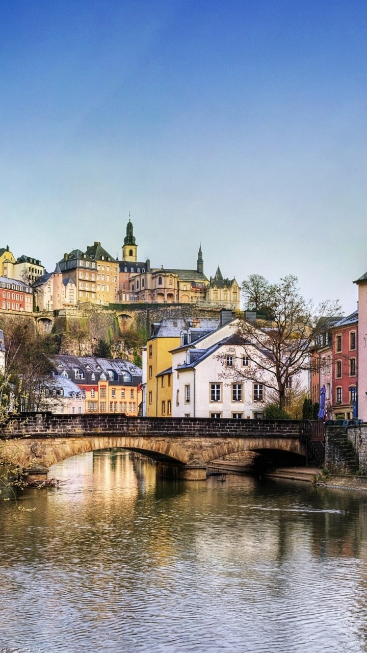 Brown and White Concrete Building Beside River Under Blue Sky During Daytime. Wallpaper in 720x1280 Resolution
