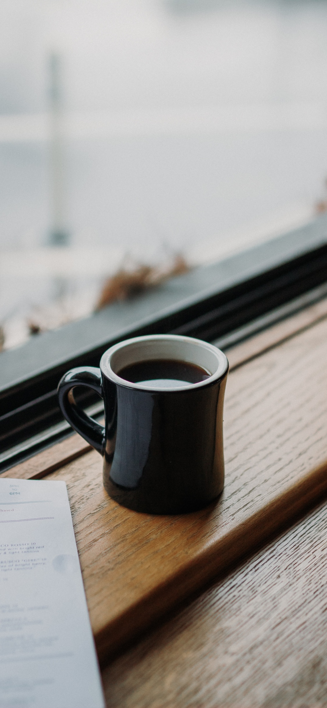 Black Ceramic Mug on Brown Wooden Table. Wallpaper in 1125x2436 Resolution