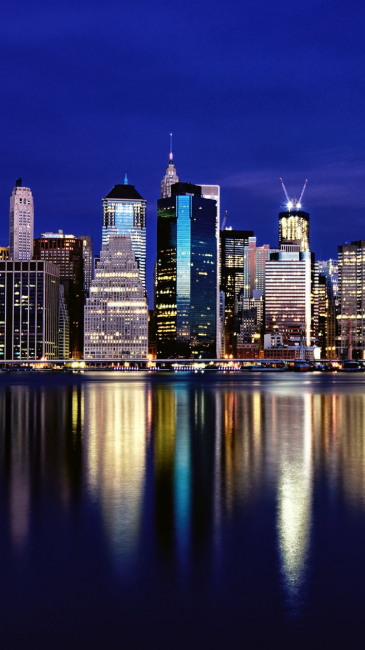 Horizonte de la Ciudad a Través Del Cuerpo de Agua Durante la Noche.. Wallpaper in 750x1334 Resolution