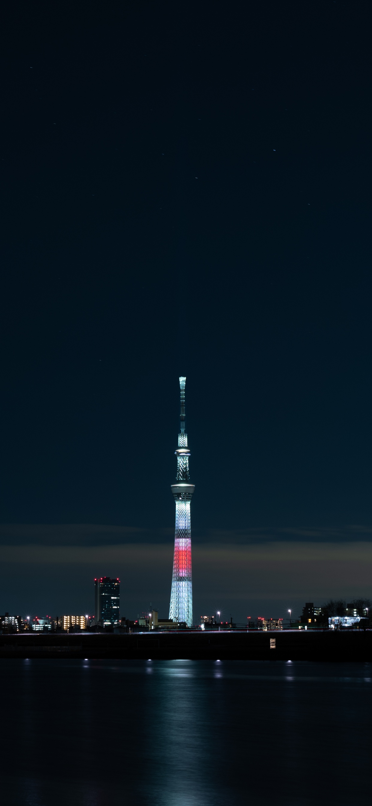 Weißer Und Roter Turm in Der Nähe Eines Gewässers Während Der Nacht. Wallpaper in 1242x2688 Resolution