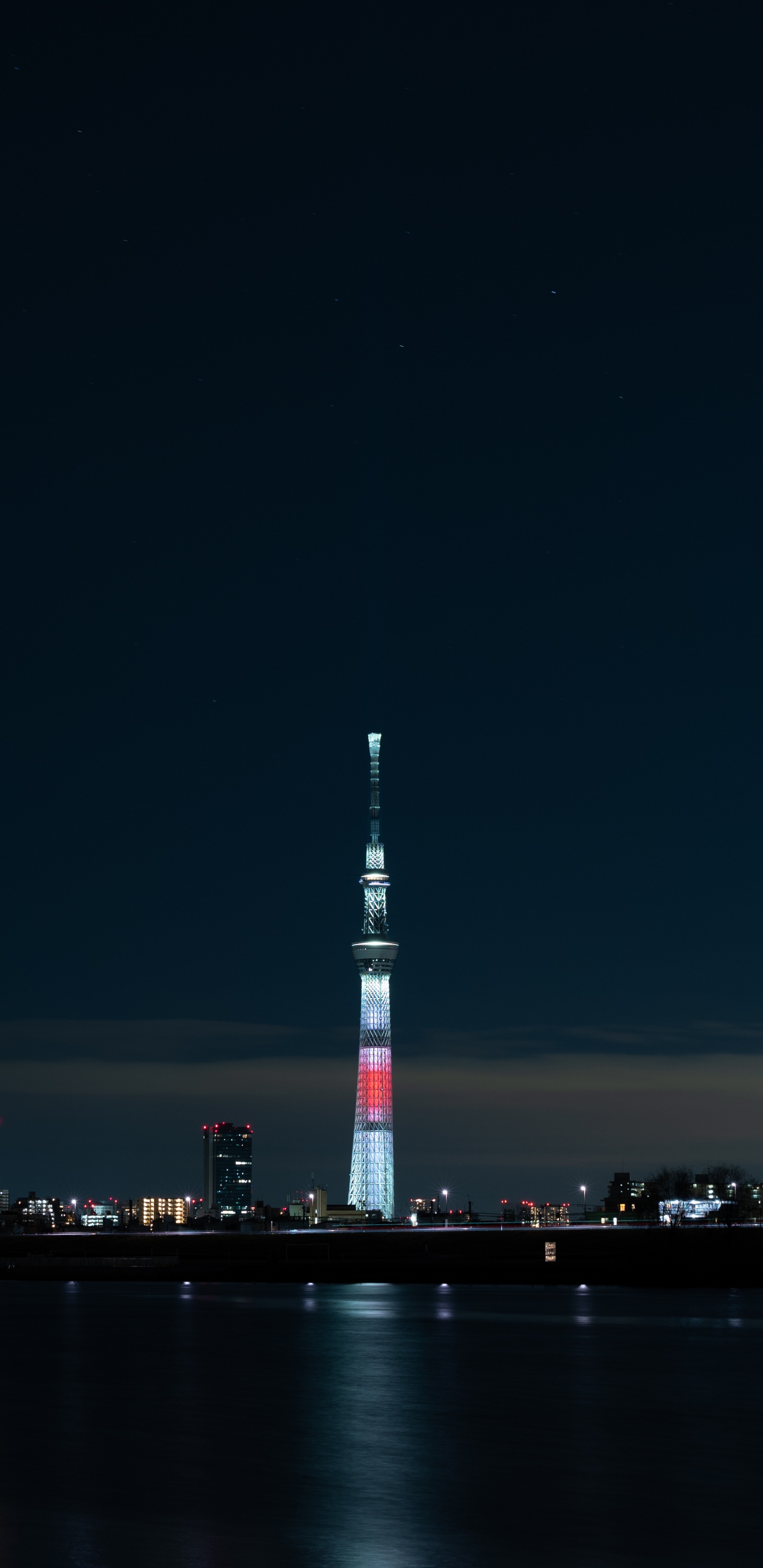 Torre Blanca y Roja Cerca Del Cuerpo de Agua Durante la Noche.. Wallpaper in 1440x2960 Resolution