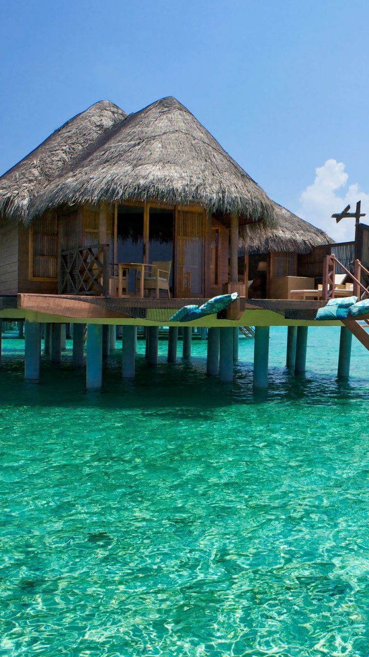 Brown Wooden Beach House on Blue Sea Under Blue Sky During Daytime. Wallpaper in 720x1280 Resolution