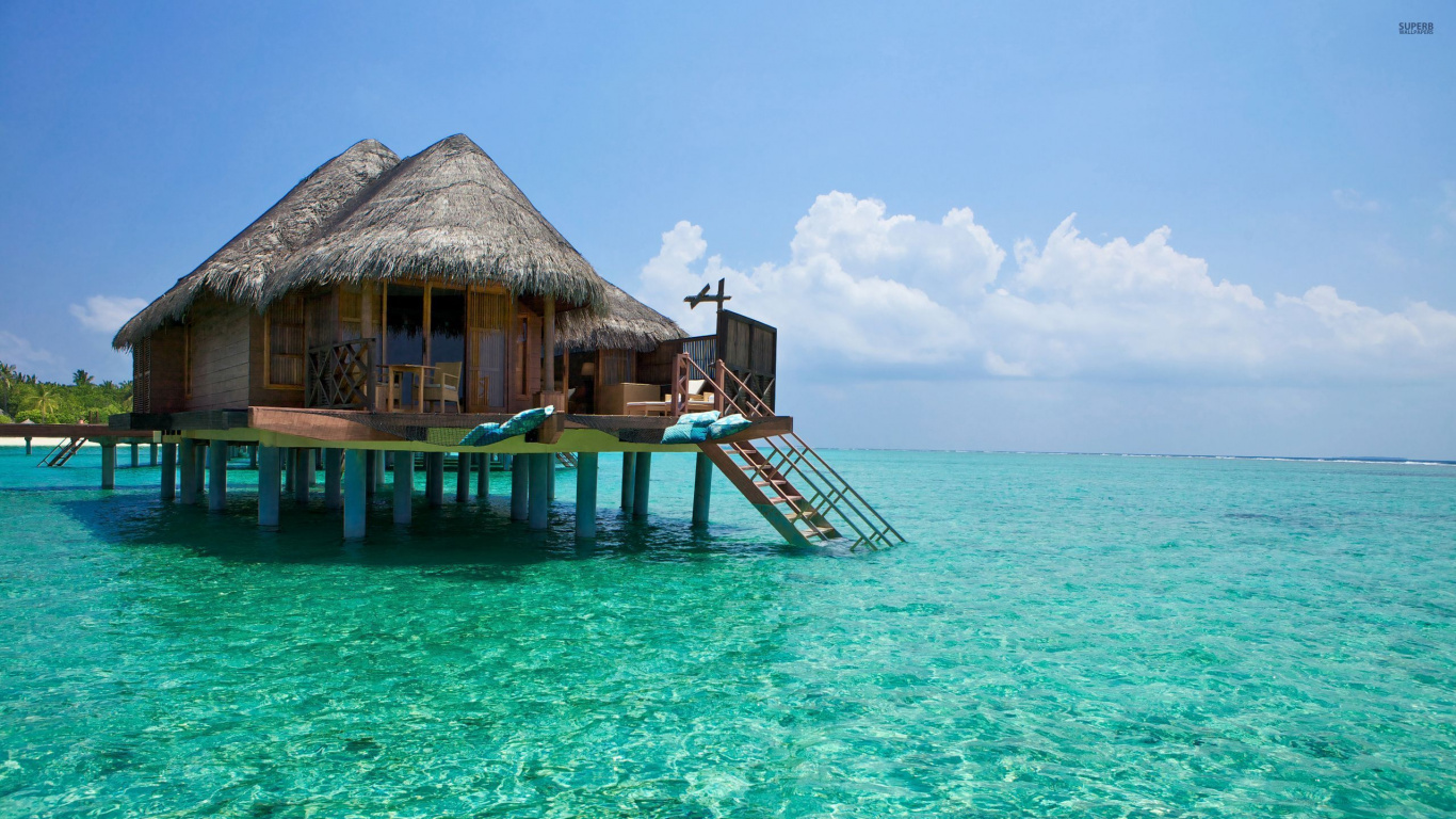 Maison de Plage en Bois Marron Sur Mer Bleue Sous Ciel Bleu Pendant la Journée. Wallpaper in 1366x768 Resolution
