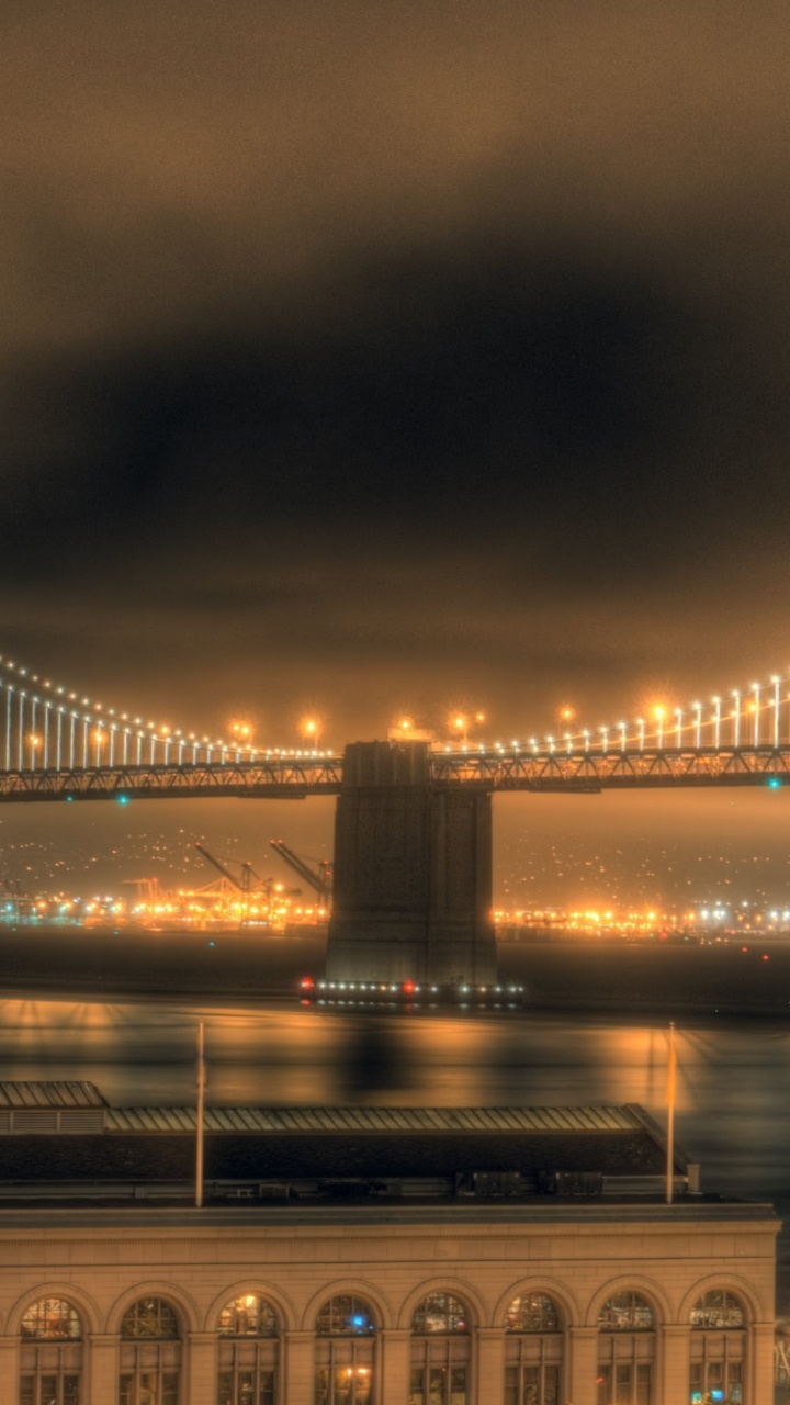 Beleuchtete Brücke Über Gewässer Während Der Nacht. Wallpaper in 720x1280 Resolution