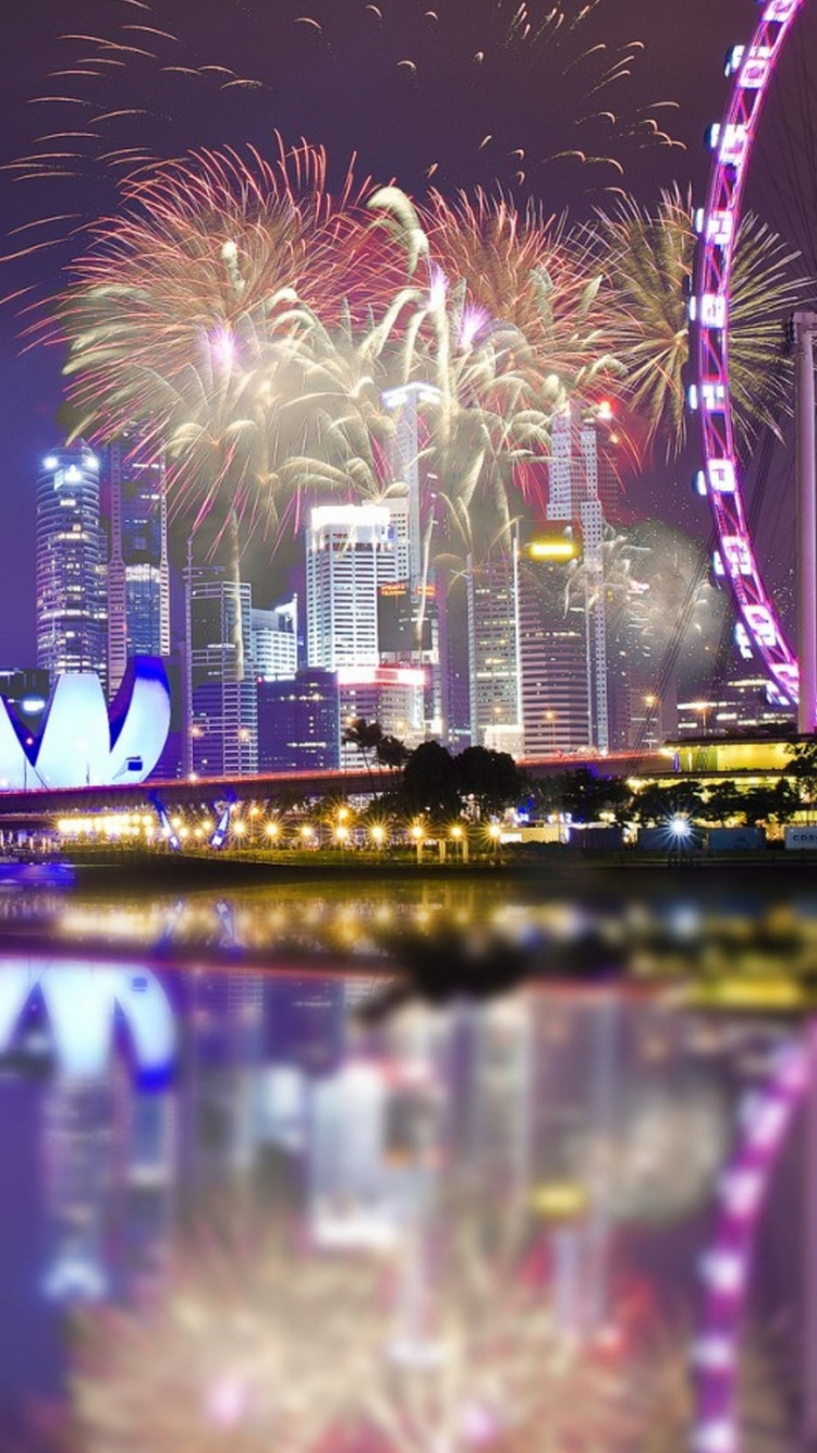 Feuerwerk Über Stadtgebäuden Während Der Nacht. Wallpaper in 750x1334 Resolution