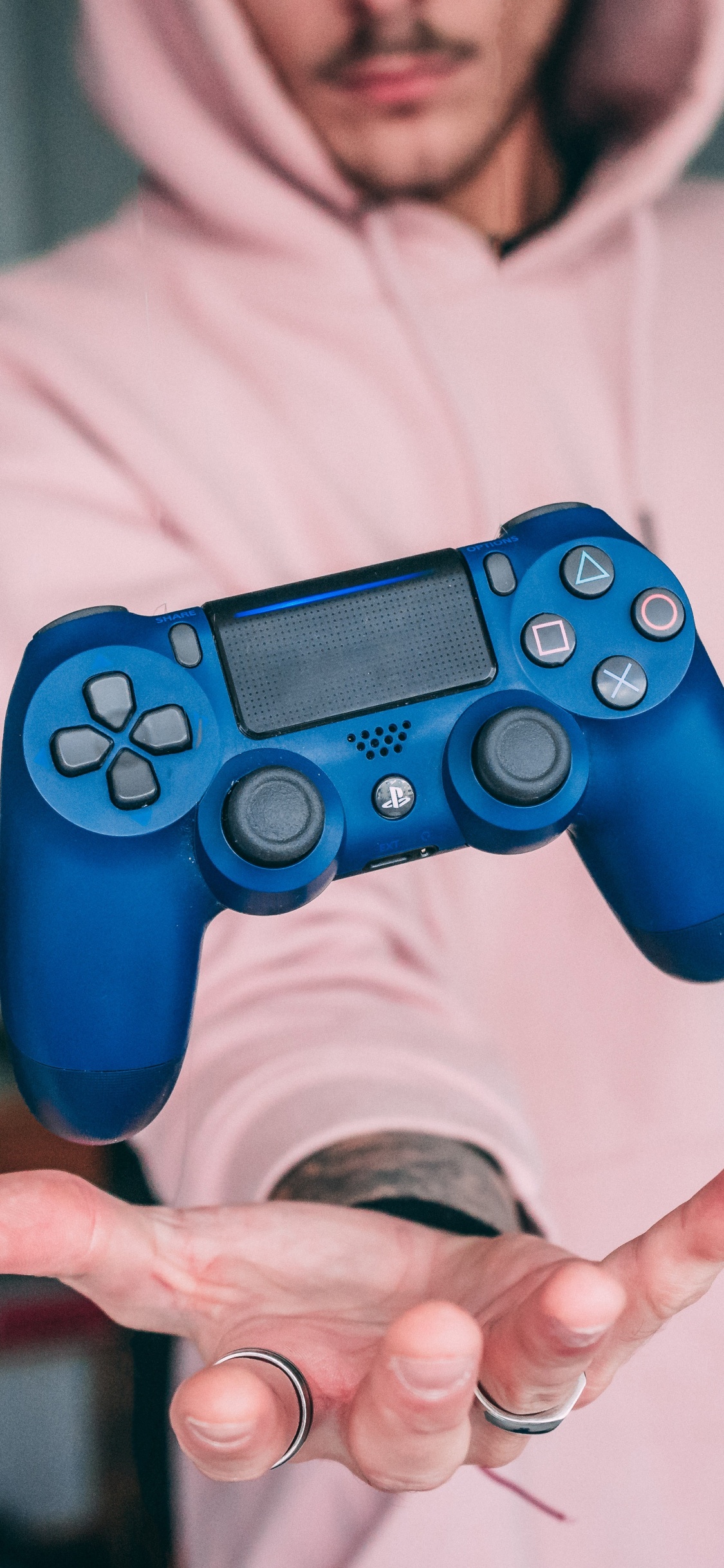 Man in White Hoodie Holding Blue Sony ps 4 Controller. Wallpaper in 1125x2436 Resolution