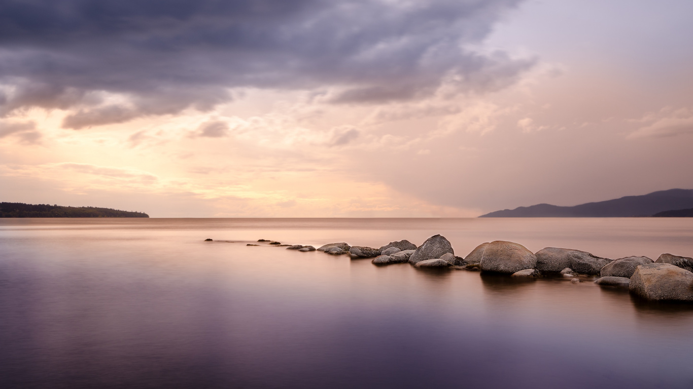 Rocas Grises en Cuerpo de Agua Bajo Nubes Grises. Wallpaper in 1366x768 Resolution