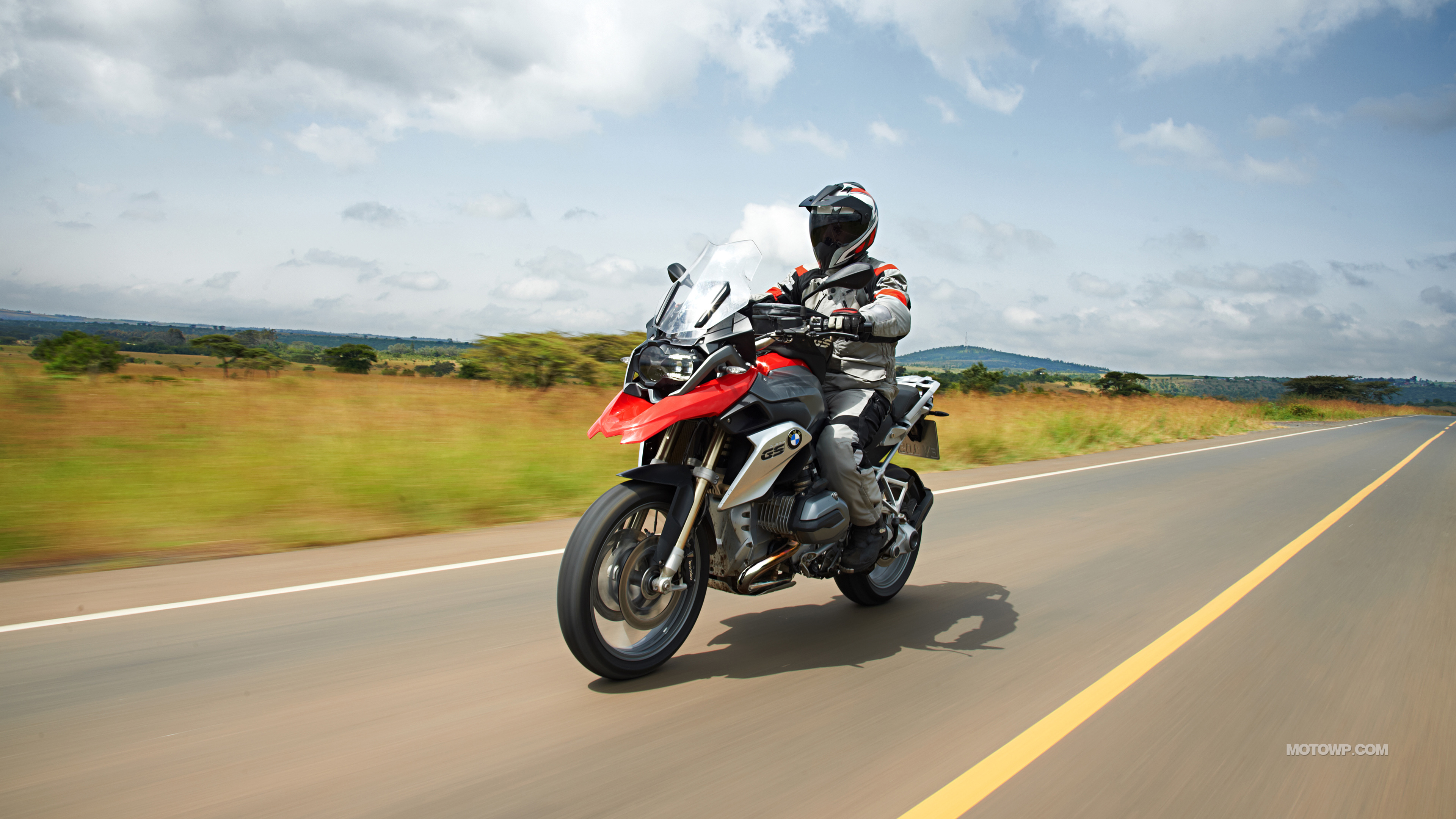 Man in Black and Red Motorcycle Suit Riding Motorcycle on Road During Daytime. Wallpaper in 3840x2160 Resolution