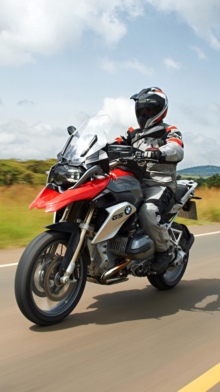 Man in Black and Red Motorcycle Suit Riding Motorcycle on Road During Daytime. Wallpaper in 750x1334 Resolution