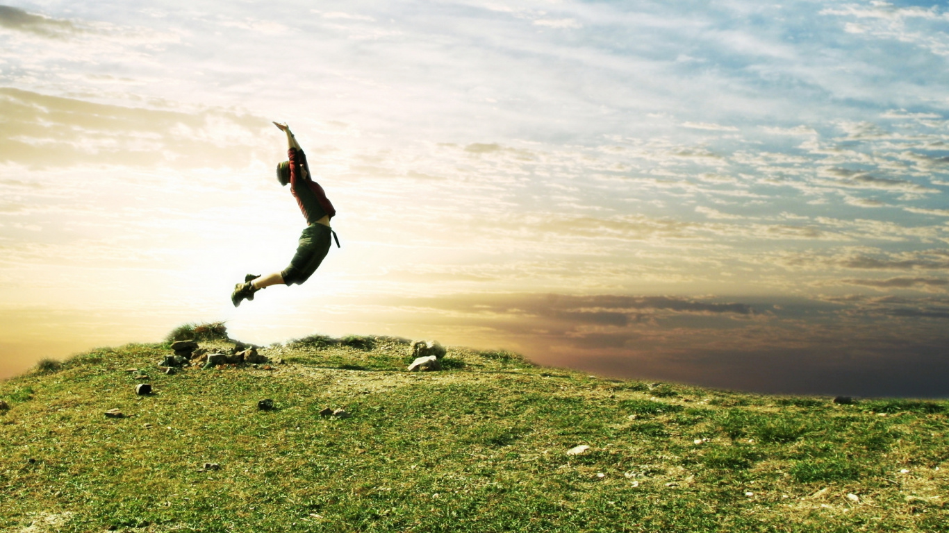 Homme en Chemise Noire et Pantalon Noir Sautant Sur Terrain D'herbe Verte Pendant la Journée. Wallpaper in 1366x768 Resolution