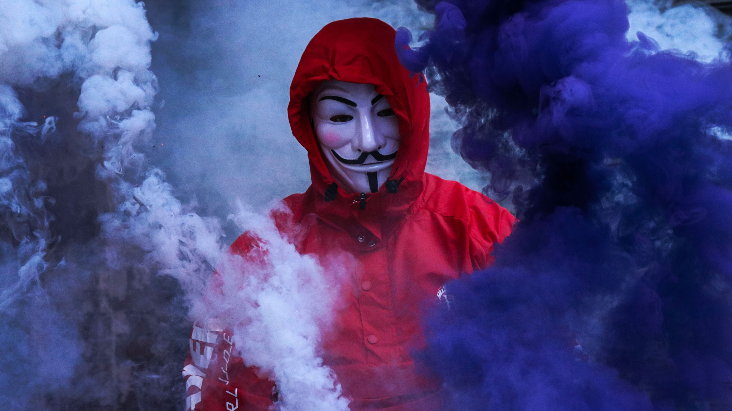 Person im Roten Hoodie Mit Roter Maske Mit Blauem Rauch. Wallpaper in 2560x1440 Resolution