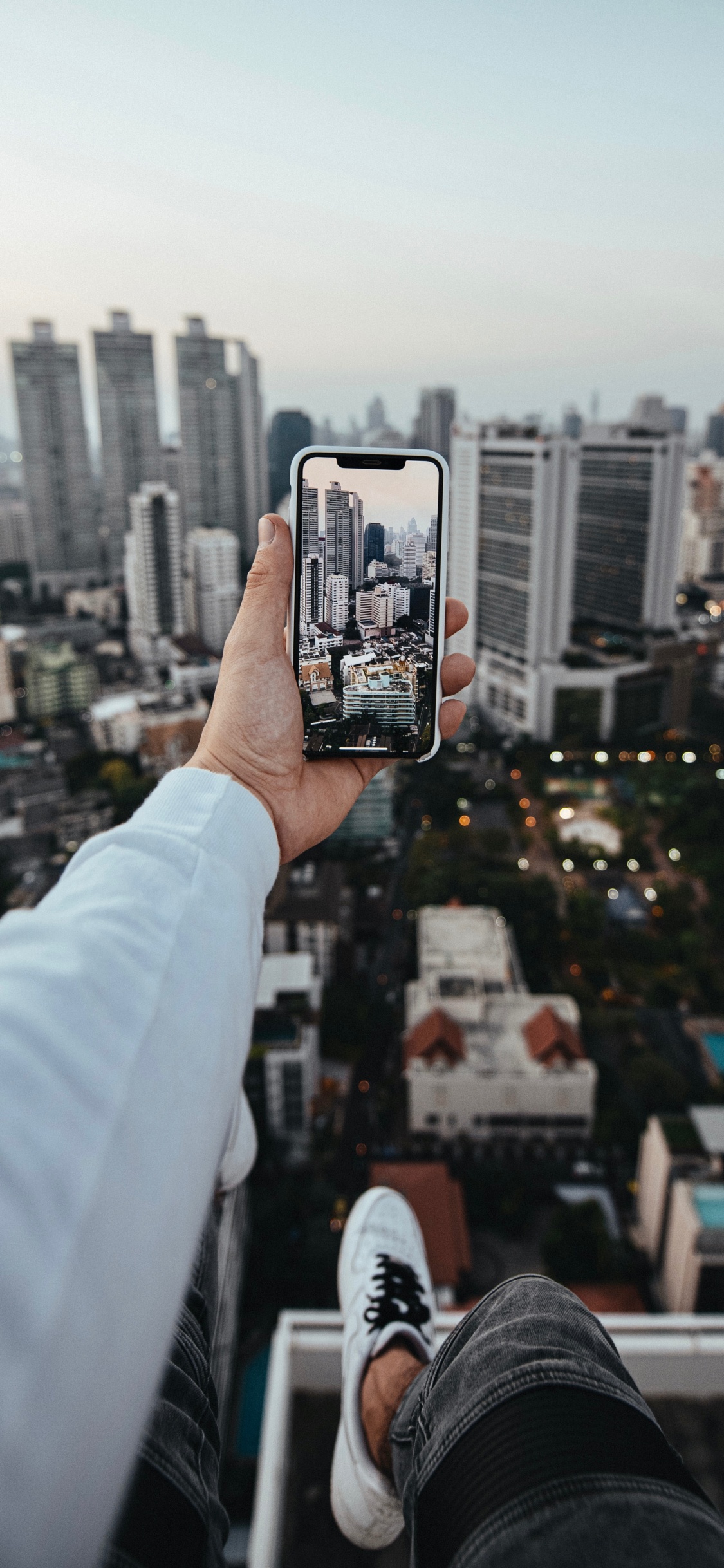 Persona Que Tiene un Teléfono Inteligente Negro Tomando Fotos de Los Edificios de la Ciudad Durante el Día. Wallpaper in 1125x2436 Resolution
