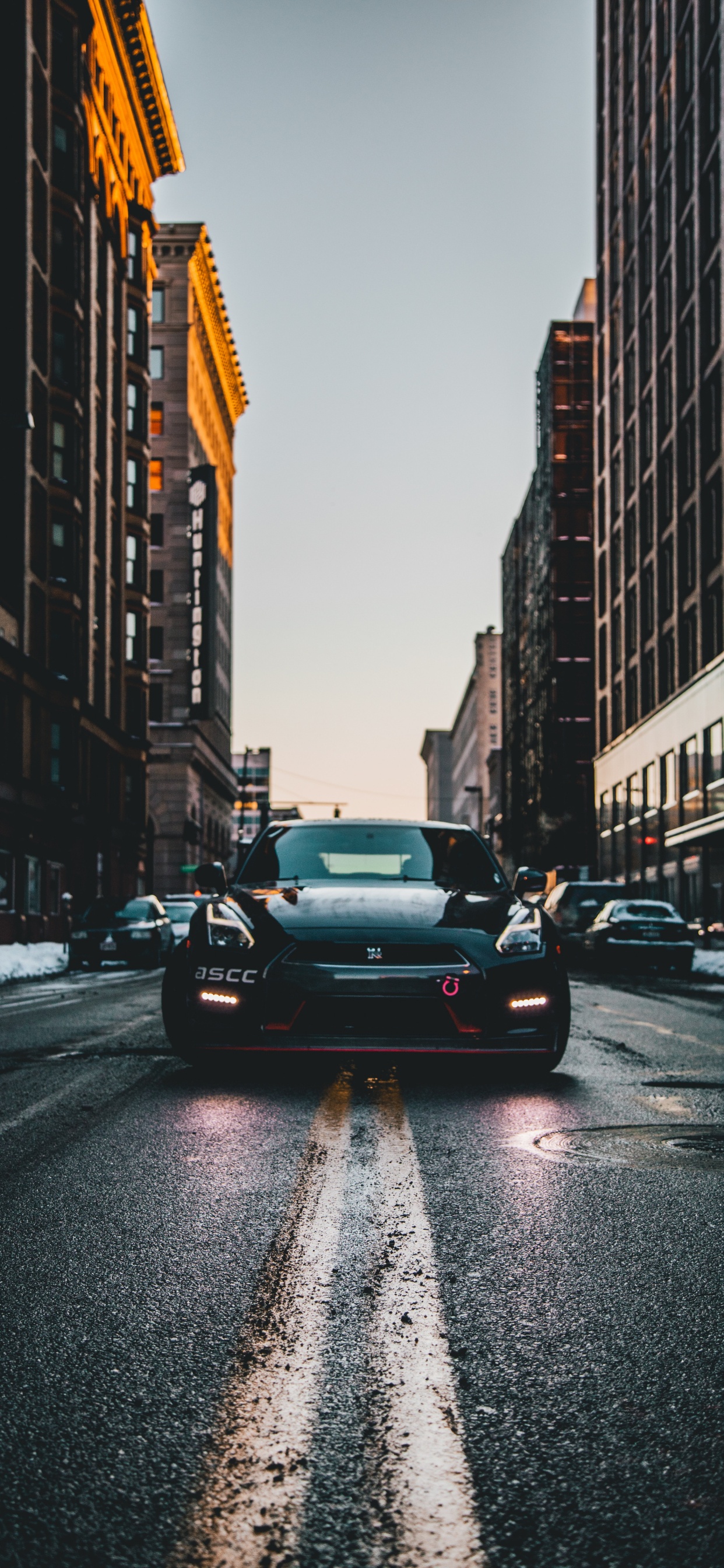 Black Sedan on Road in Between High Rise Buildings During Daytime. Wallpaper in 1242x2688 Resolution