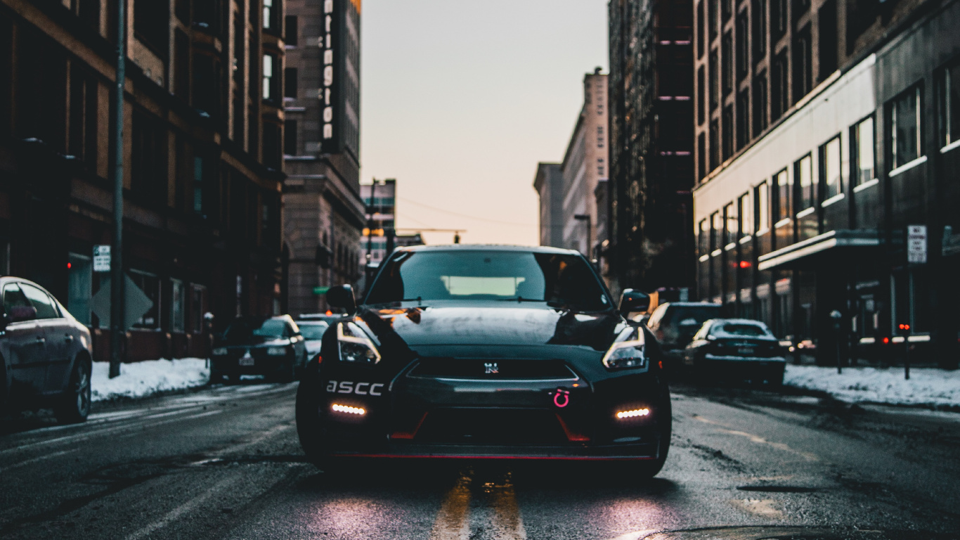 Black Sedan on Road in Between High Rise Buildings During Daytime. Wallpaper in 1366x768 Resolution