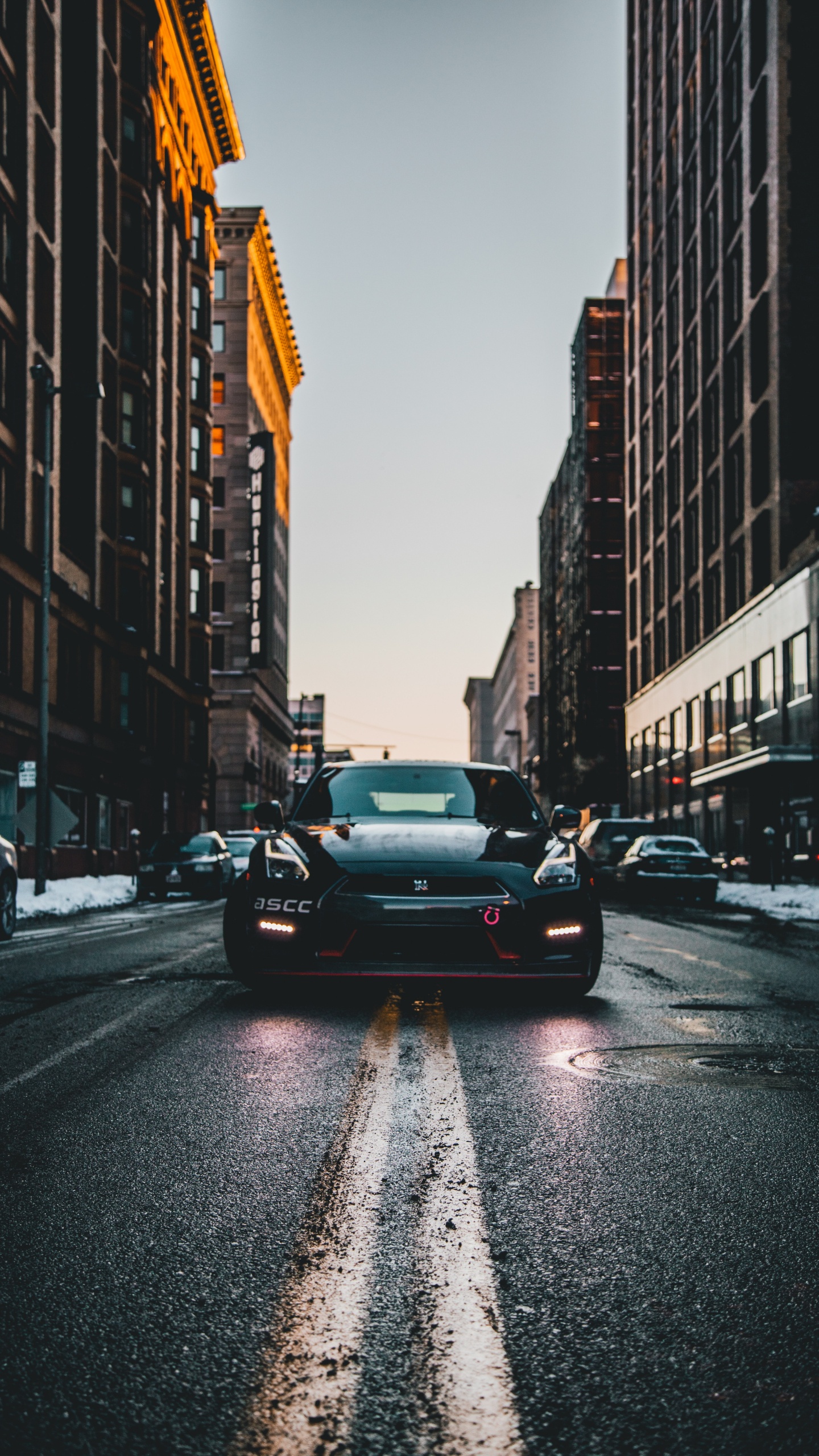 Black Sedan on Road in Between High Rise Buildings During Daytime. Wallpaper in 1440x2560 Resolution