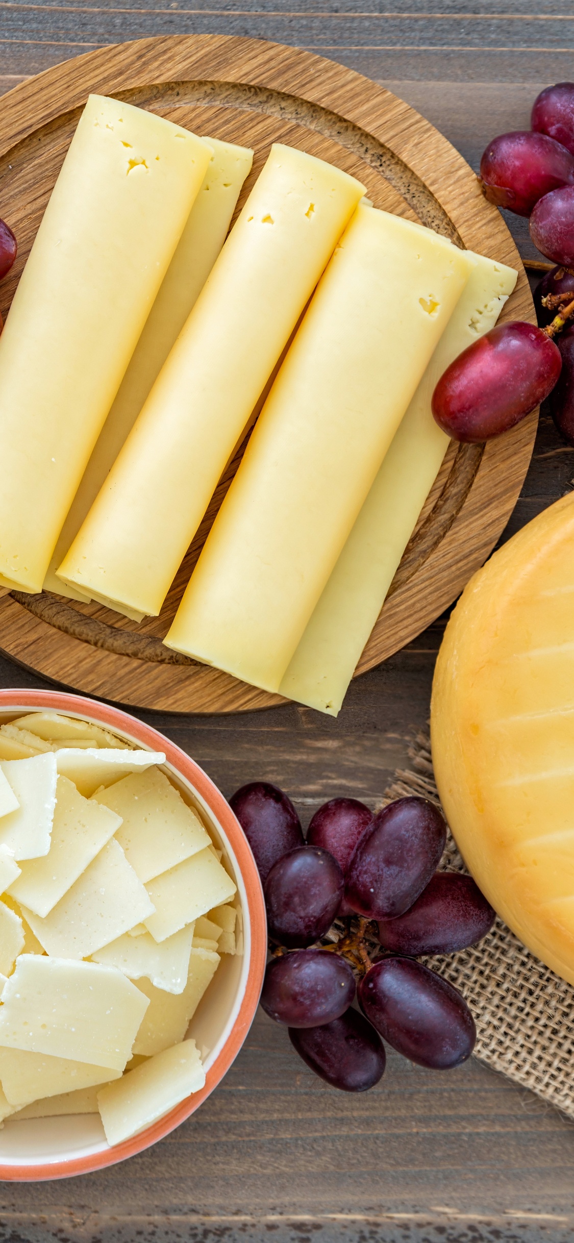 Geschnittener Käse Auf Braunem Holzschneidebrett. Wallpaper in 1125x2436 Resolution