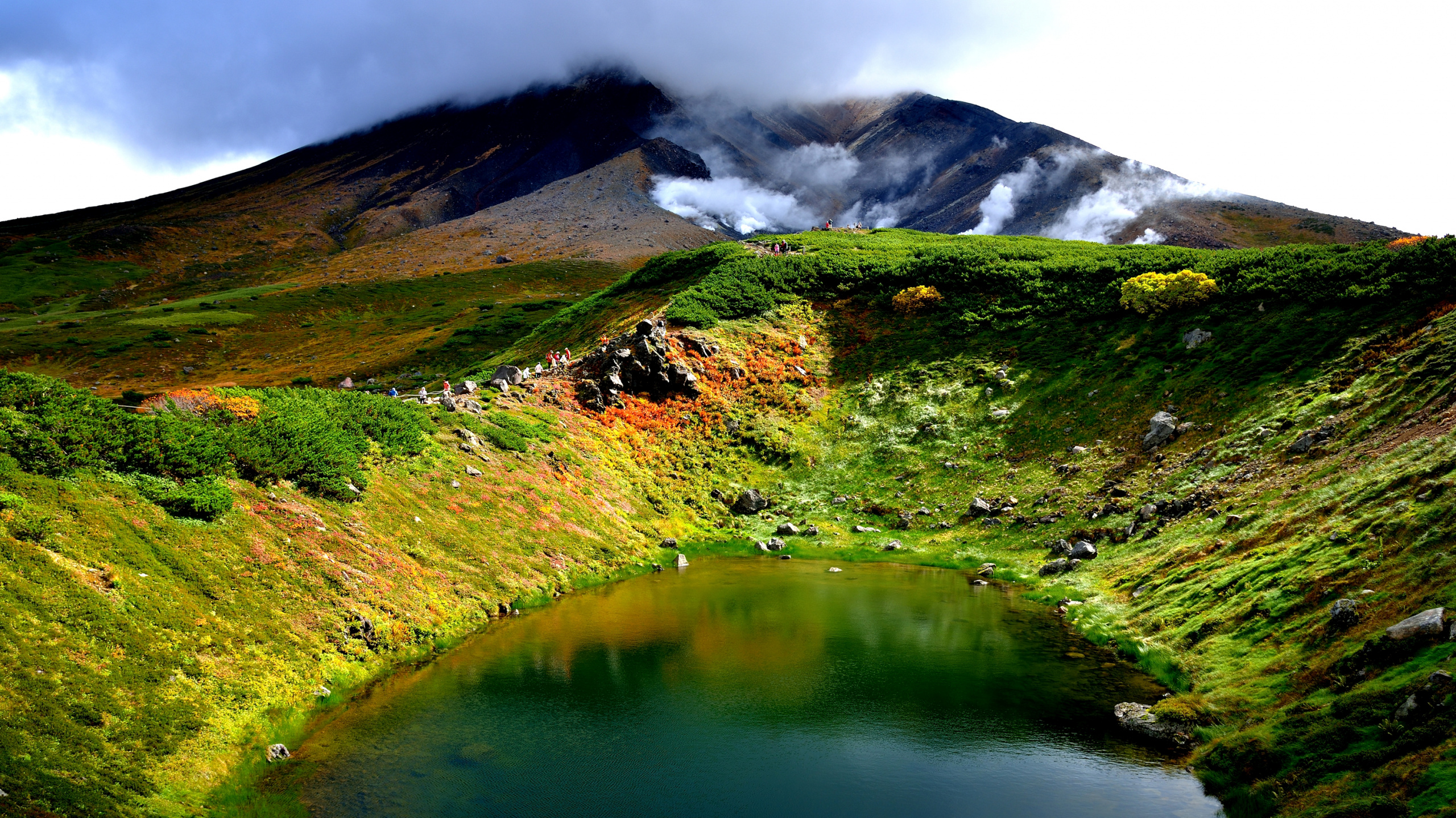 Montagne Verte et Brune à Côté du Lac Pendant la Journée. Wallpaper in 2560x1440 Resolution
