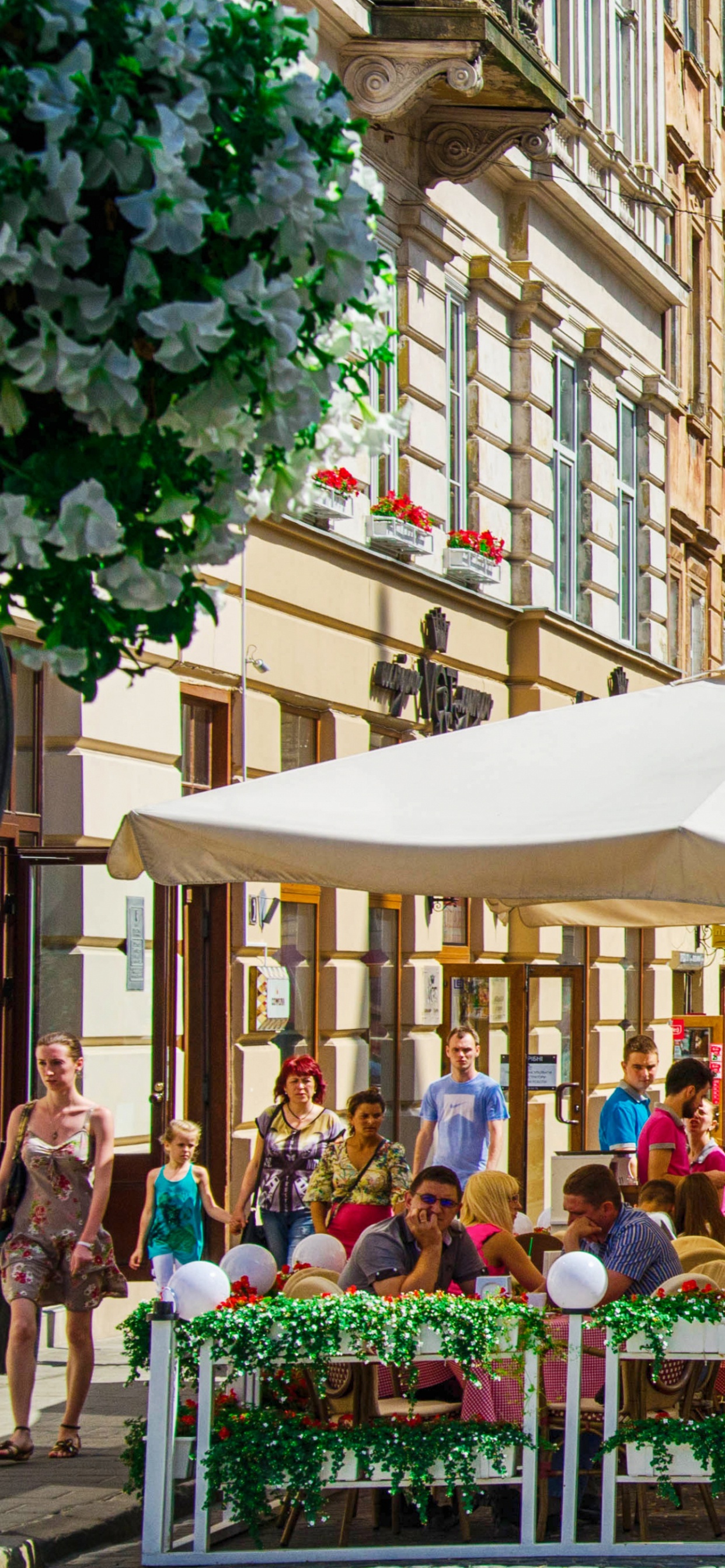 People Sitting on Bench Near Brown Concrete Building During Daytime. Wallpaper in 1242x2688 Resolution