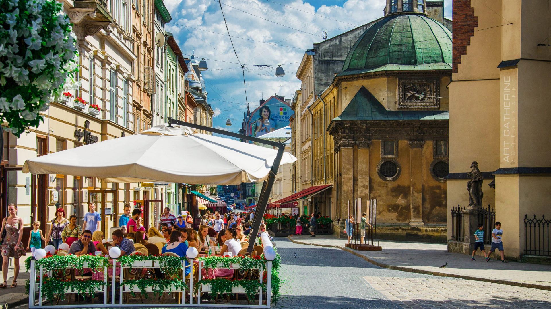 People Sitting on Bench Near Brown Concrete Building During Daytime. Wallpaper in 1920x1080 Resolution