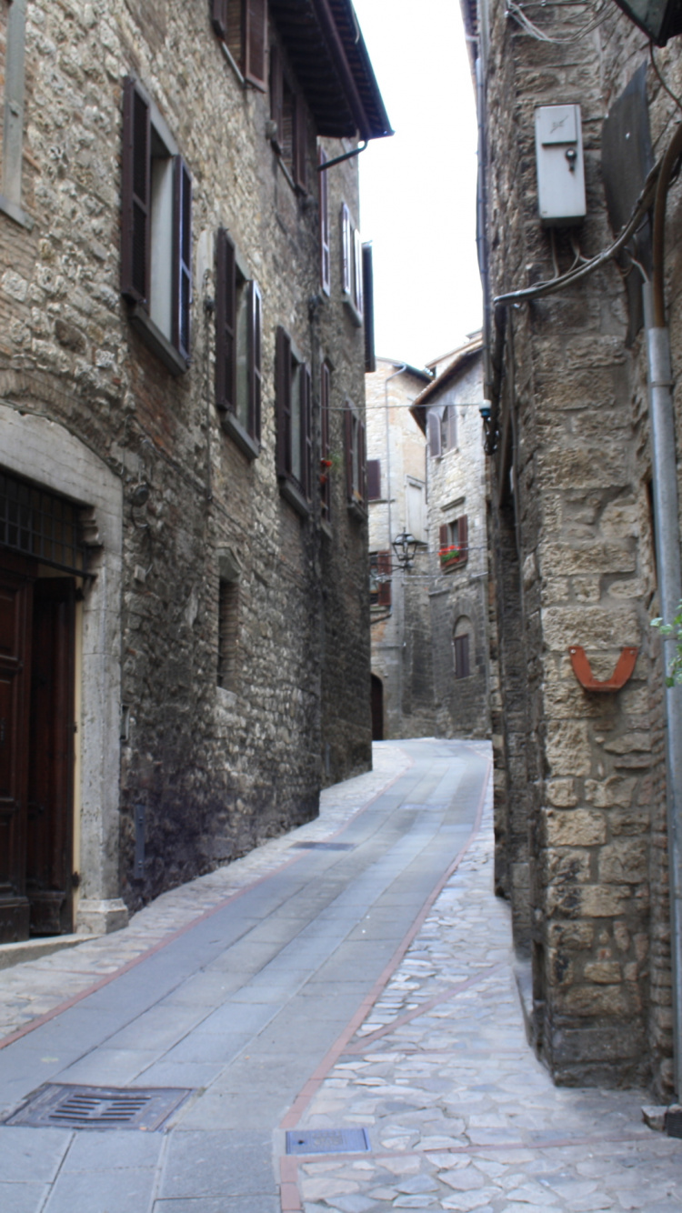 Gray Concrete Pathway Between Brown Brick Buildings During Daytime. Wallpaper in 750x1334 Resolution