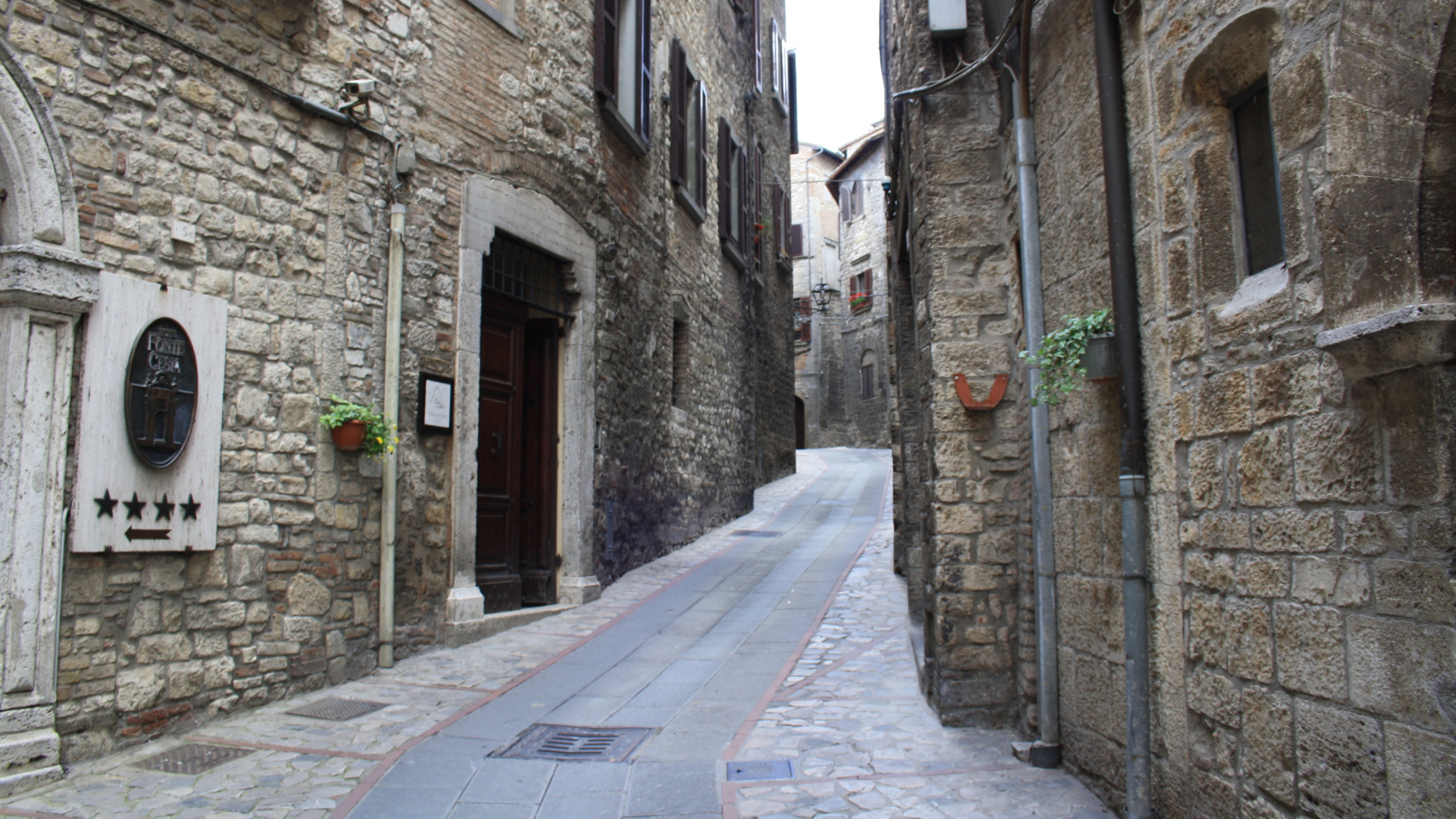 Grauer Betonweg Zwischen Braunen Backsteingebäuden Tagsüber. Wallpaper in 2560x1440 Resolution