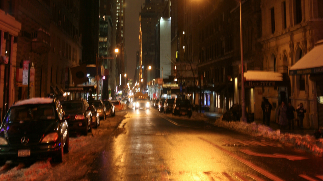 Autos Auf Der Straße Zwischen Hochhäusern Während Der Nacht. Wallpaper in 1280x720 Resolution