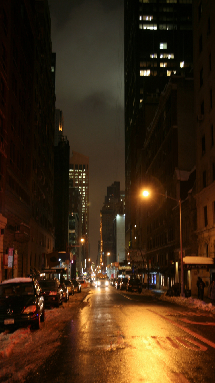 Cars on Road Between High Rise Buildings During Night Time. Wallpaper in 750x1334 Resolution