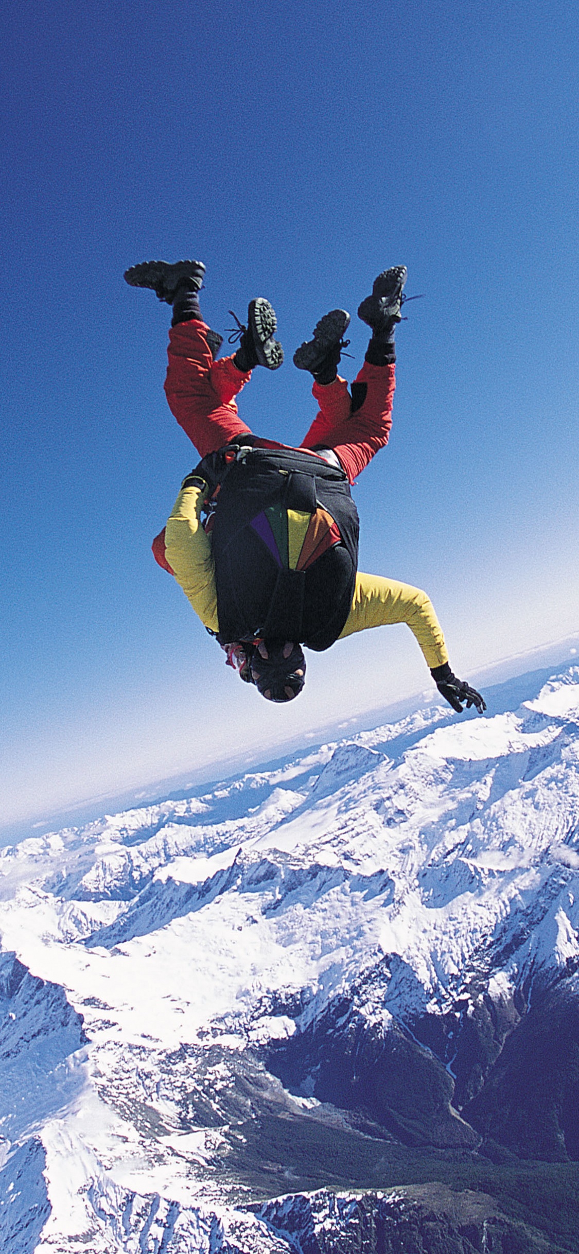 Man in Black Jacket and Black Pants Jumping on Snow Covered Mountain During Daytime. Wallpaper in 1125x2436 Resolution