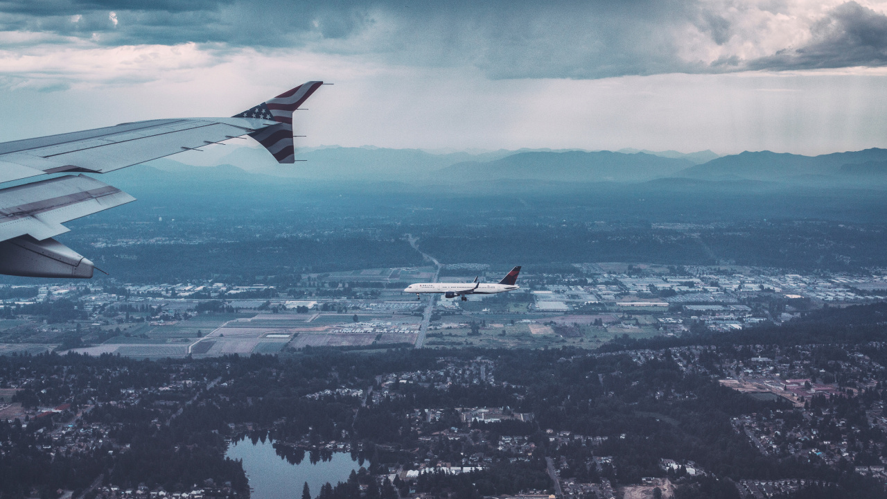 Weißes Und Rotes Flugzeug, Das Tagsüber Über Die Stadt Fliegt. Wallpaper in 1280x720 Resolution