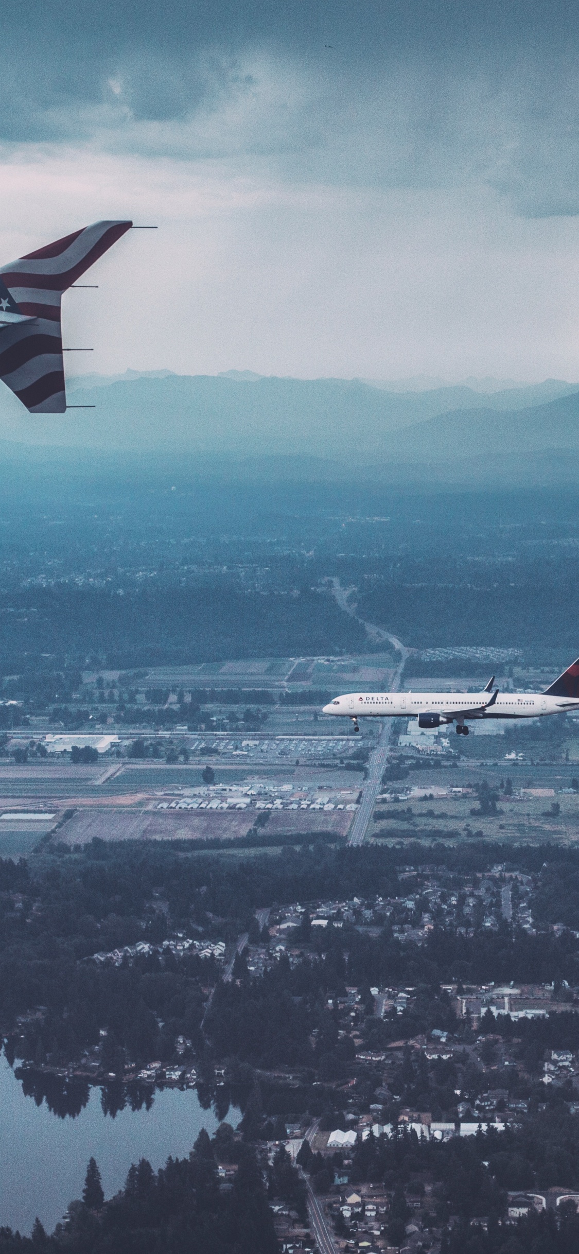 White and Red Airplane Flying Over City During Daytime. Wallpaper in 1125x2436 Resolution